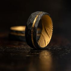 a black and gold wedding band on top of a table