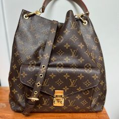 Authentic Louis Vuitton Hand Bag. This Handbag Is A Perfect Combination Of Style, Luxury And Functionality. Brown Monogram Canvas With Gold Hardware. Bag Has Exterior Pocket, Leather Top Handle, And Adjustable Removable Strap. Handbag Is In Good Condition Minor Wear On Base And Corners . Adjustable Strap Is New And Has Never Been Used. Box To New Strap Included And Also Original Dust Cover Everyday Luxury Monogram Canvas Satchel Shoulder Bag, Monogram Canvas Satchel For Everyday Luxury, Everyday Luxury Monogram Canvas Shoulder Bag With Detachable Strap, Luxury Everyday Monogram Canvas Shoulder Bag With Detachable Strap, Everyday Luxury Monogram Canvas Bag With Branded Hardware, Everyday Monogram Canvas Shoulder Bag With Branded Hardware, Gold Signature Coated Canvas Bag For Everyday, Brown Signature Coated Canvas Bag For Everyday Luxury, Louis Vuitton Metis