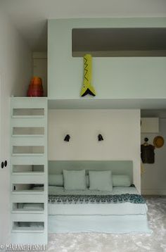 a white bed sitting under a loft next to a ladder