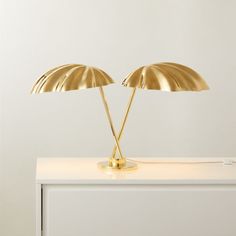 two golden lamps sitting on top of a white table