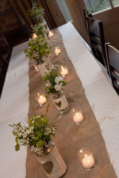 a long table with candles and vases filled with flowers on top of the table