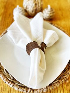 a white plate topped with two napkins on top of a wooden table next to sea shells