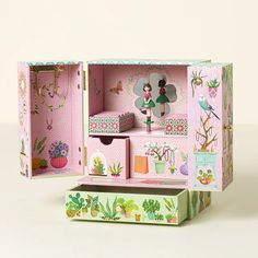 a pink dollhouse with lots of accessories inside it's display case on a white surface