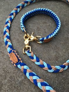 a blue and tan braided dog leash with brass hardware on concrete ground next to rock