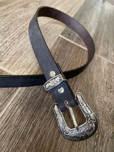 This gorgeous belt is one of our most popular products. We offer it in 4 colors of premium 8-9 ounce buffalo leather and in a tooled leather finished in antique tan. Features a beautiful western floral buckle, loop and tip. Your choice of buffalo leather in matte black, crazy horse brown, crazy horse gray, or golden brown or tooled and finished in saddle tan. The western floral buckle, loop and tip are die cast and set in a beautiful antiqued silver plate. 1.0-inch width. Cut to your personal si Western Style Silver Belt Buckle, Silver Hand-tooled Belt For Western-themed Events, Silver Hand Tooled Belt For Western-themed Events, Horse Brown, Popular Products, Western Belts, Buffalo Leather, Tooled Leather, Crazy Horse