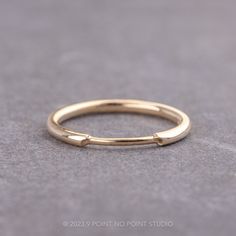 a gold wedding band on a gray surface