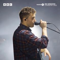 a man holding a microphone up to his mouth while standing in front of a microphone