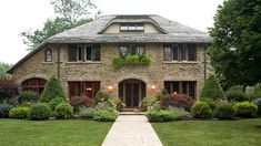 a large brick house with lots of windows and plants on the front lawn, along with a walkway leading up to it