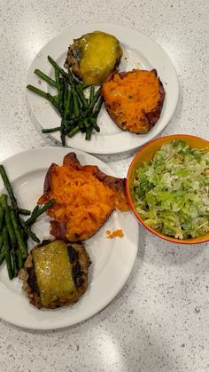 two white plates topped with meat and veggies next to a bowl of coleslaw