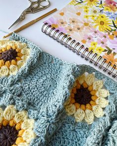 a crocheted blanket with sunflowers on it next to a pair of scissors