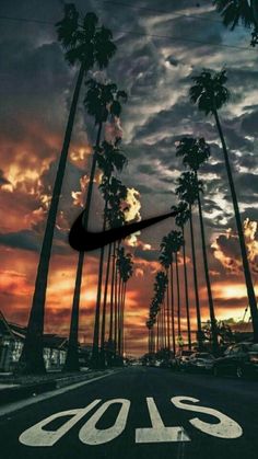 the sun is setting behind palm trees in front of a sky with clouds and a nike logo