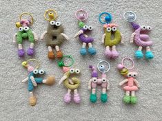 several crocheted stuffed animals are arranged on the floor with keychains in front of them