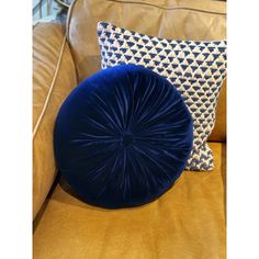 a blue round pillow sitting on top of a brown couch next to two other pillows