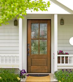 the front door of a white house with flowers