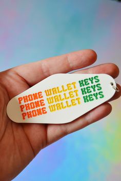 a hand holding a cell phone wallet keychain that says phone wallet hey's phone wallet keys