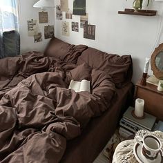 an unmade bed with brown sheets and pillows