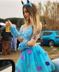 a woman in a blue dress with purple polka dots on her skirt holding a bottle