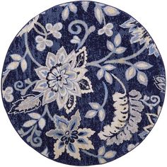 a blue rug with white flowers and leaves on it's side, in the shape of a circle