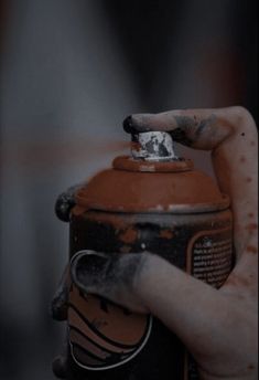 a hand holding an orange and black fire extinguisher's can with rust on it