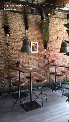 an empty restaurant with brick walls and wooden tables in the center, surrounded by potted plants