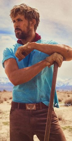 a man in blue shirt holding a wooden stick