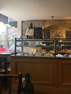 a counter in a restaurant with lots of food on it and people sitting at the tables