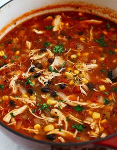 a pot filled with chicken tortilla soup and garnished with cilantro