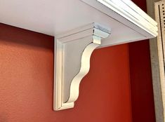 a close up of a white shelf on a red wall