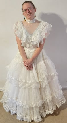 a woman wearing a white dress with ruffles on it