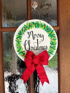 a merry christmas door hanger with a red bow