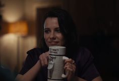 a woman holding up a coffee mug with the words i don't know what she is