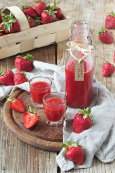 fresh strawberries sit on a wooden table next to a bottle of juice and two glasses