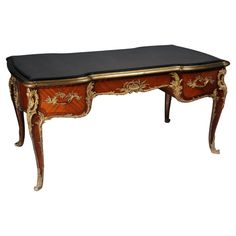 an antique desk with black top and gold trimming