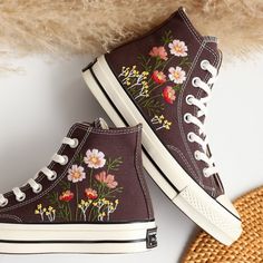 a pair of brown high top sneakers with floral embroidered on the side and white laces