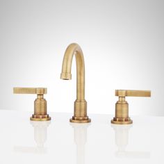 two brass faucets on a white surface