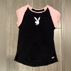 This Black Vintage Tee Features A Playboy Logo On The Front, A Round Neckline With Pink Trim, And Pink Cap Sleeves. The T-Shirt Is Made Of 100% Combed Cotton Material. The Playboy Bunny Logo Is Prominently Displayed On The Front Of The Black Shirt With Pink Accents. This Item Is Perfect For Casual Occasions And Is Available In Size Medium. The Shirt Has A Regular Fit And Is Very Stretchy. It Is A Great Addition To Any Wardrobe And Is Sure To Turn Heads. It’s Brand New, Never Wort, But I Marked I Cute Black Tops For Streetwear, Cute Black Top For Streetwear, Black Logo Print Top For Loungewear, Playboy Logo, Bunny T Shirt, Bunny Logo, Pink Cap, Kawaii Stuff, Bunny Outfit