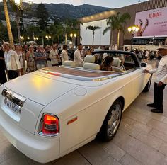 a white car parked in front of a crowd of people