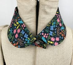 the collar is decorated with colorful flowers on black and white fabric, while it sits on a mannequin's torso