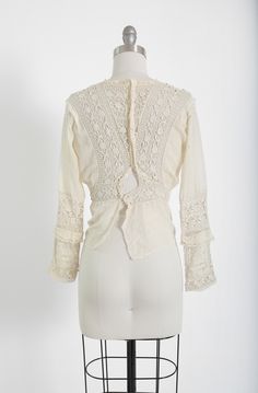 "Stunning Antique vintage early 1900's Edwardian crochet blouse Floral embroidered crochet lace, high neck long sleeve Natural cotton in ivory / cream button down back Great vintage condition - few age spots (see photos) very wearable M e a s u r e m e n t s: Size: fits like a XS S BUST: 18 1/2\" Waist: 13\" Total Length: 22\" Sleeves: 20\" Label: unbranded Fabric: cotton +All Measurements are taking while garment is lying flat+ + Jewelry, belts, and any other accessories are NOT included unless Spring Vintage Lace Crochet Top, Spring Vintage Crochet Top With Lace Work, Long Sleeve Cotton Crochet Top With Lace Trim, Long Sleeve Crochet Cotton Top With Lace Trim, Cotton Crochet Top With Lace Trim, Fitted Long Sleeve Cotton Lace Top, Fitted Elegant Cotton Crochet Top, Elegant Fitted Cotton Crochet Top, Bohemian Long Sleeve Lace Top With Lace Cuffs