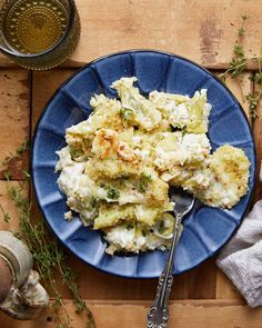 a blue plate topped with mashed potatoes next to a glass of water and silverware