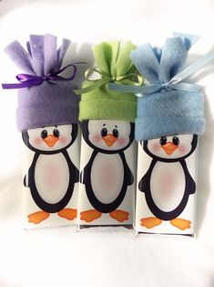 three penguins with hats on their heads are wrapped in toilet paper and tied to twine