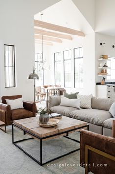 a living room with couches, tables and chairs in front of large windows on the wall