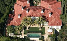 an aerial view of a house with a pool and palm trees in the foreground