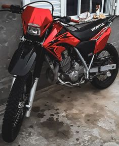 a red and black motorcycle parked next to a building