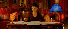 a young man sitting at a table in front of a lamp