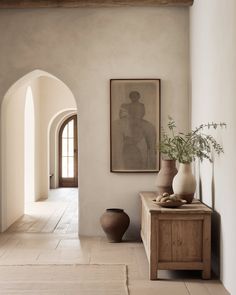 a hallway with an arched doorway and two vases on the side table next to it