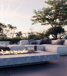 a fire pit sitting on top of a cement slab next to a couch and table