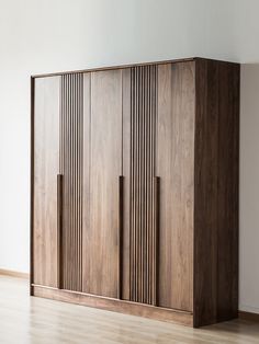 a wooden cabinet sitting on top of a hard wood floor next to a white wall