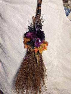 a broom decorated with flowers and leaves on a white sheet