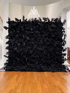 a large black rug on top of a hard wood floor next to a chandelier